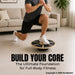 A man in a home setting balances on a circular stability board while wearing a dark gray t-shirt, black shorts, and white sneakers. Large text at the bottom reads 'BUILD YOUR CORE The Ultimate Foundation for Full-Body Fitness'.
